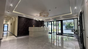 A modern hotel lobby with a reception desk, a chandelier, and large glass doors leading outside. - DSF GARDEN HOTEL (Tashkent)