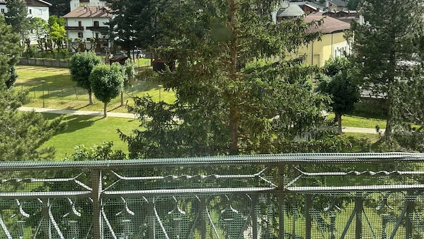 Un barrio residencial con casas, un parque con césped y montañas al fondo.