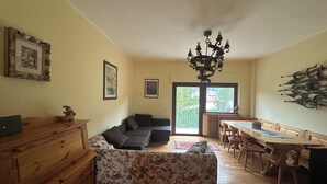 Un salón espacioso con sofá, muebles de madera, una araña y una mesa de comedor.