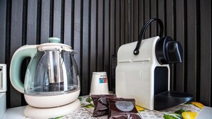 Una cocina con hervidor, cafetera y dos sobres de café.