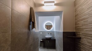 Un baño moderno con un espejo redondo, un lavamanos y un perchero para toallas.