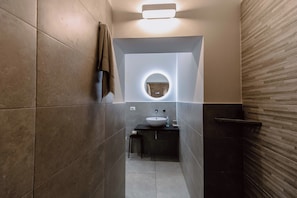 A modern bathroom with a round mirror, a sink, and a towel rack. - 2 bedroom apartment in syracuse (Siracusa)
