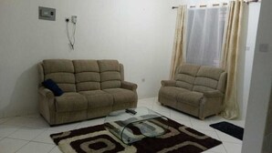 Una sala de estar con dos sofás beige, una mesa de centro de cristal y un tapete estampado.