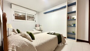 Un dormitorio con dos camas, una estantería empotrada y una ventana con vistas.
