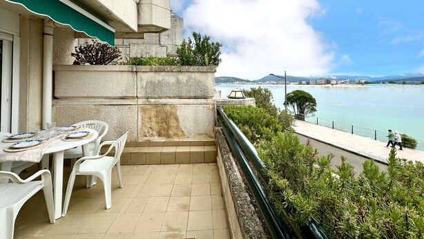 Un balcón con una mesa lista para comer, con vistas a una masa de agua y una costa distante.