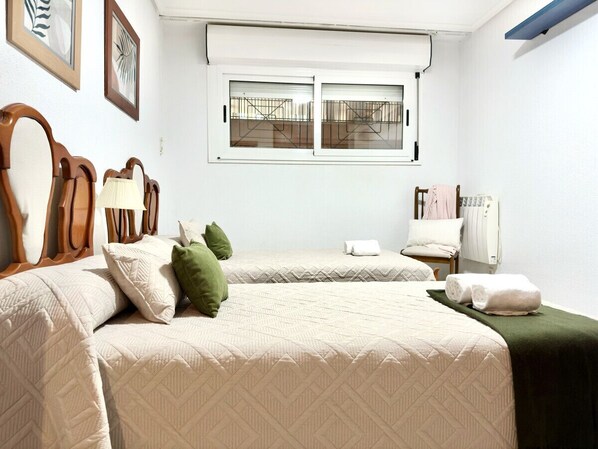 Una habitación de hotel con dos camas, una ventana con persianas, un radiador y un tendedero para toallas.