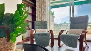 Una sala de estar moderna con un ventanal grande, dos sillones, una mesita de centro y una planta en maceta.