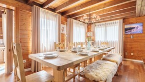 A wooden dining room with a long table set for six, benches, and a chandelier. - Gorgeous home in Gérardmer with sauna (Gérardmer)