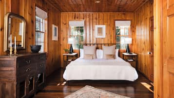 A wooden-paneled bedroom with a bed, nightstands, a dresser, and a mirror.