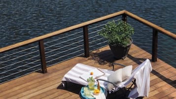 A deck with lounge chairs and a table, overlooking a body of water.