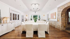A spacious dining room with a long table, white cabinetry, and a stone fireplace. - Private 37 Acre Lake Estate on 164 Acres - 11 BR (Highland)