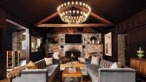 A cozy living room with a stone fireplace, leather sofas, and a wooden ceiling.