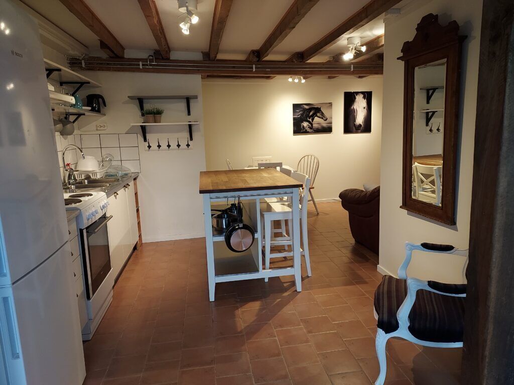 A kitchen with a wooden table, white chairs, and a hanging pot rack.