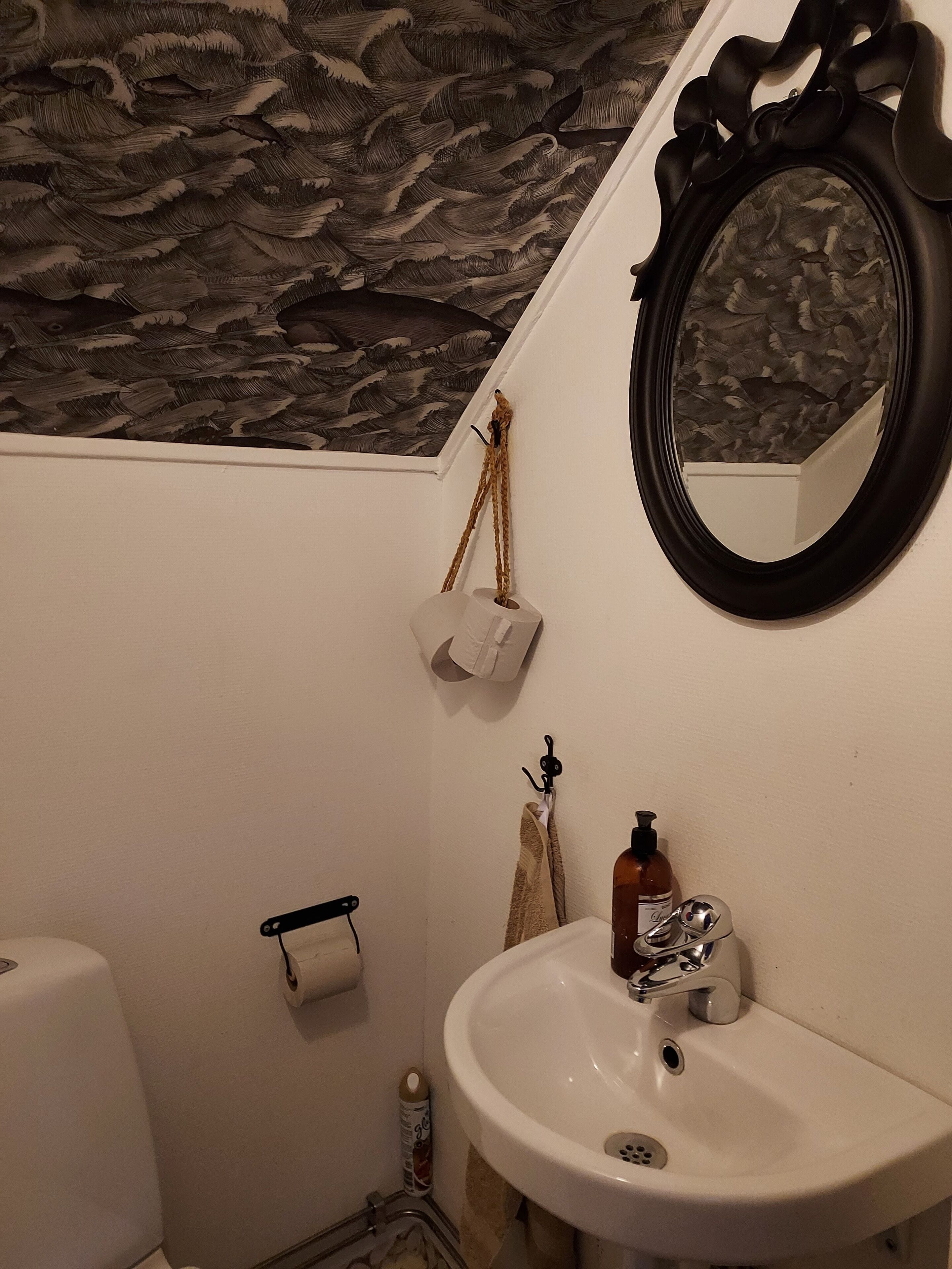 Un baño con lavamanos blanco, espejo y retrete.