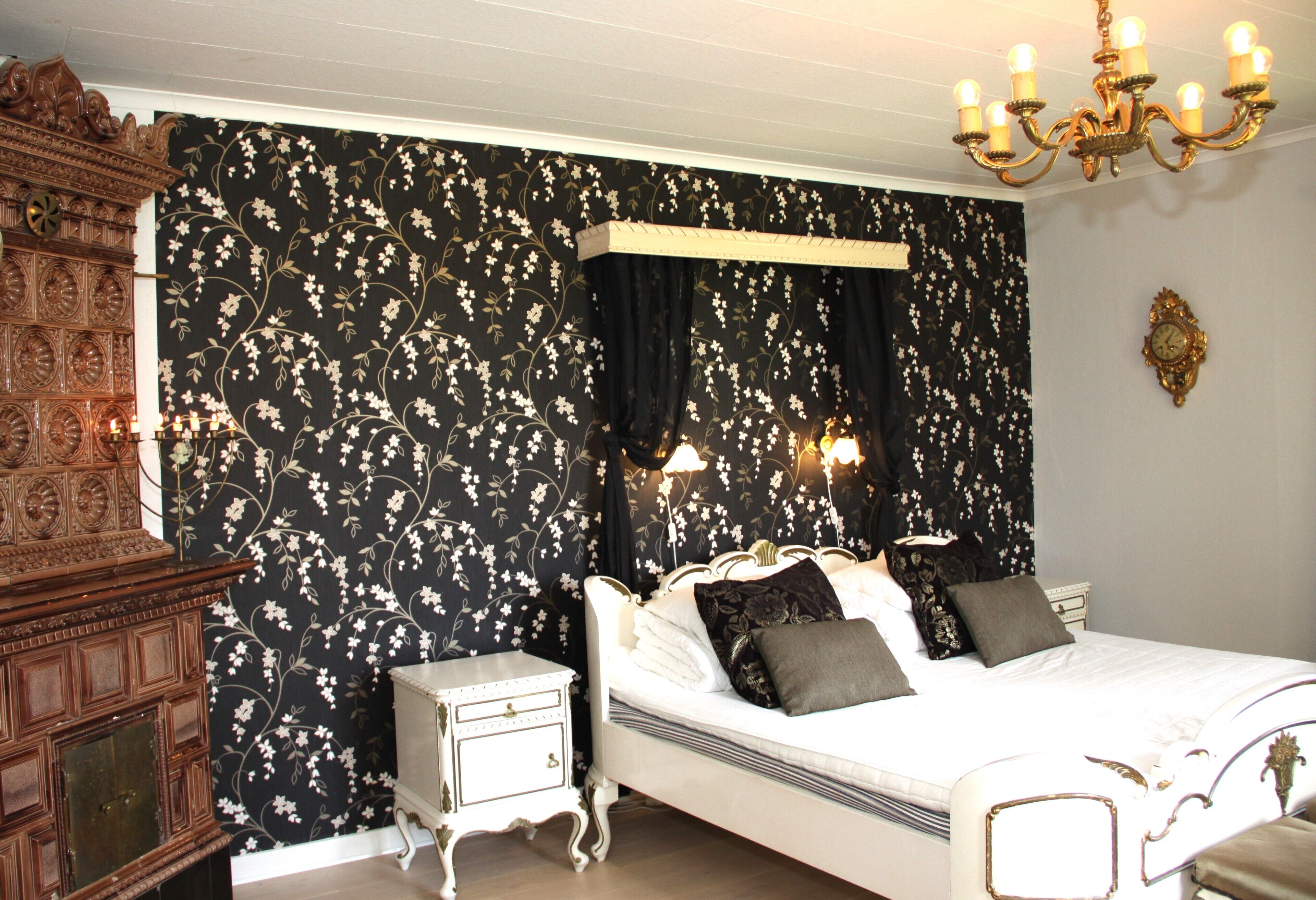 A bedroom with a large bed, a nightstand, a wooden cabinet, and a chandelier.