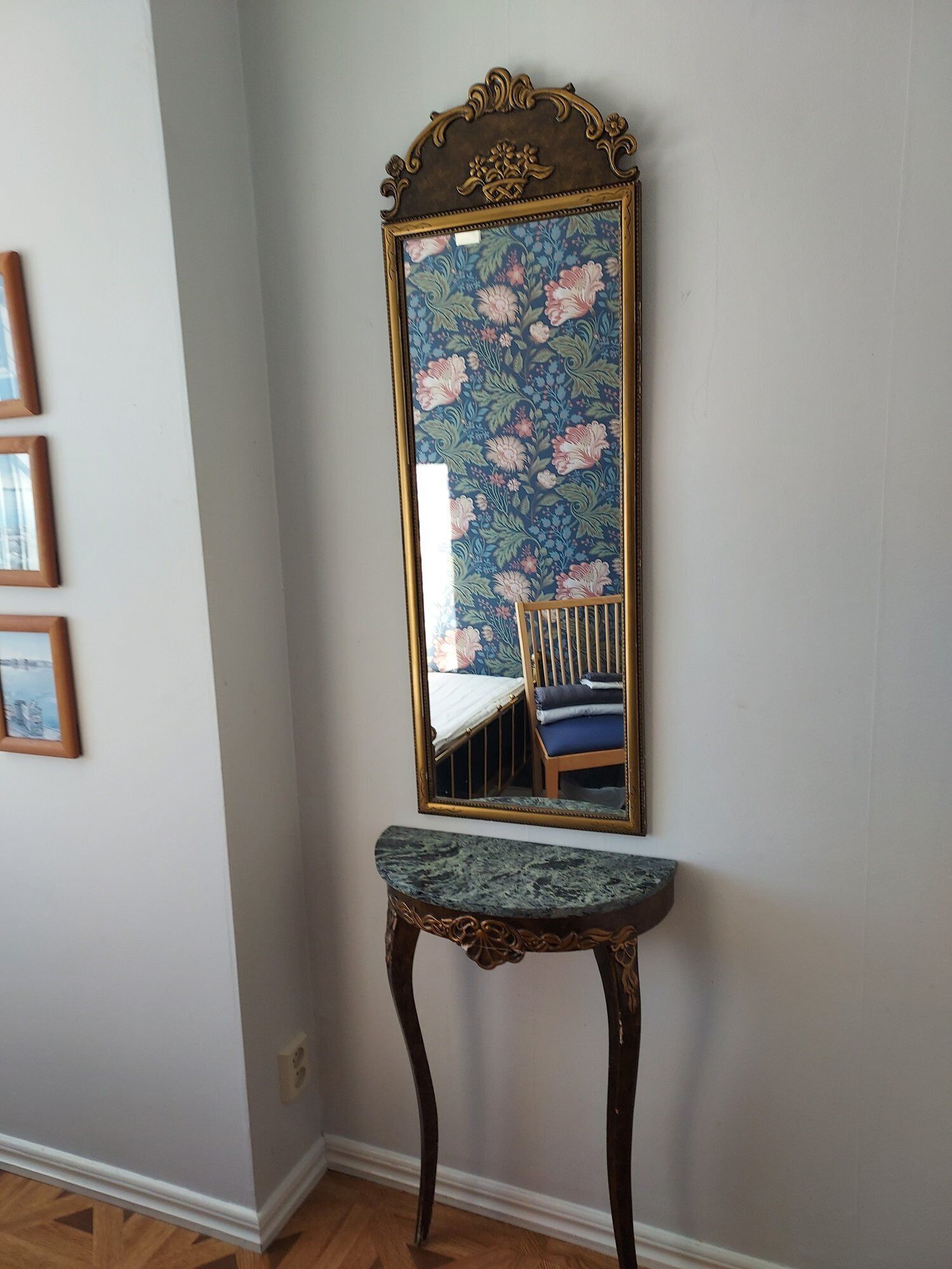 A mirror with a floral pattern, mounted on a wall above a marble console table.
