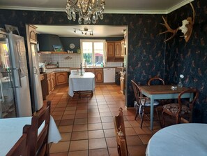 A kitchen with wooden cabinets, a dining table, and a chandelier. - älgbergets b&b (Ucklum)