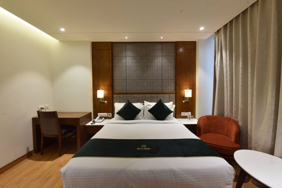 A hotel room with a large bed, two bedside tables, a desk, a chair, and a small table.