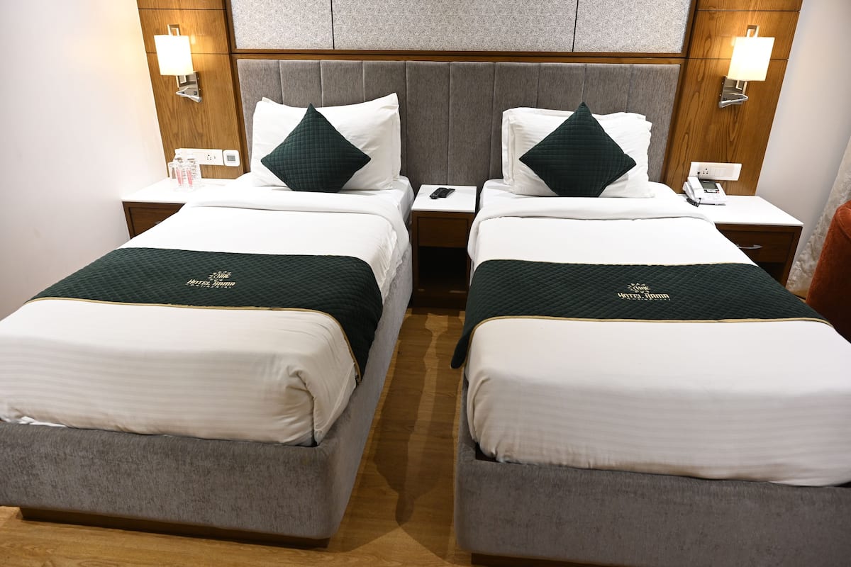 A hotel room with two beds, each with a pillow, a bedside table with a lamp, and a phone.