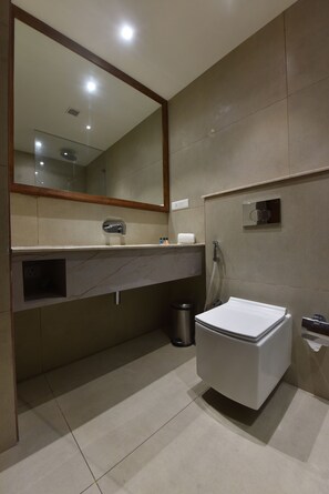 Un baño moderno con un espejo grande, un inodoro, un lavabo y una ducha.