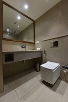 Un baño moderno con un espejo grande, un inodoro, un lavabo y una ducha.