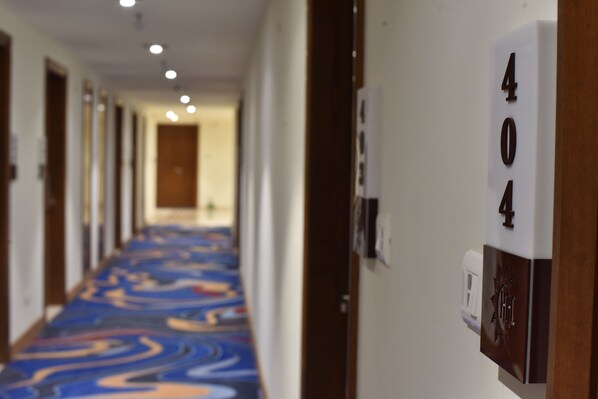 Un pasillo de hotel con una alfombra estampada, puertas a ambos lados y una placa con el número 404.