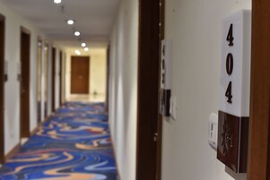 Un pasillo de hotel con una alfombra estampada, puertas a ambos lados y una placa con el número 404.