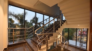 Una escalera moderna con barandas de vidrio y vistas a palmeras afuera.