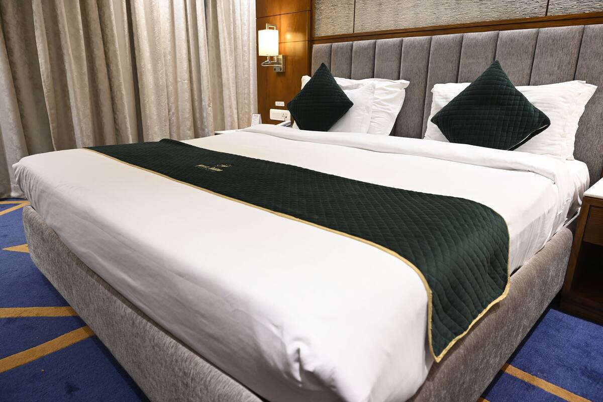 A hotel room with a large bed, a headboard, and a nightstand.