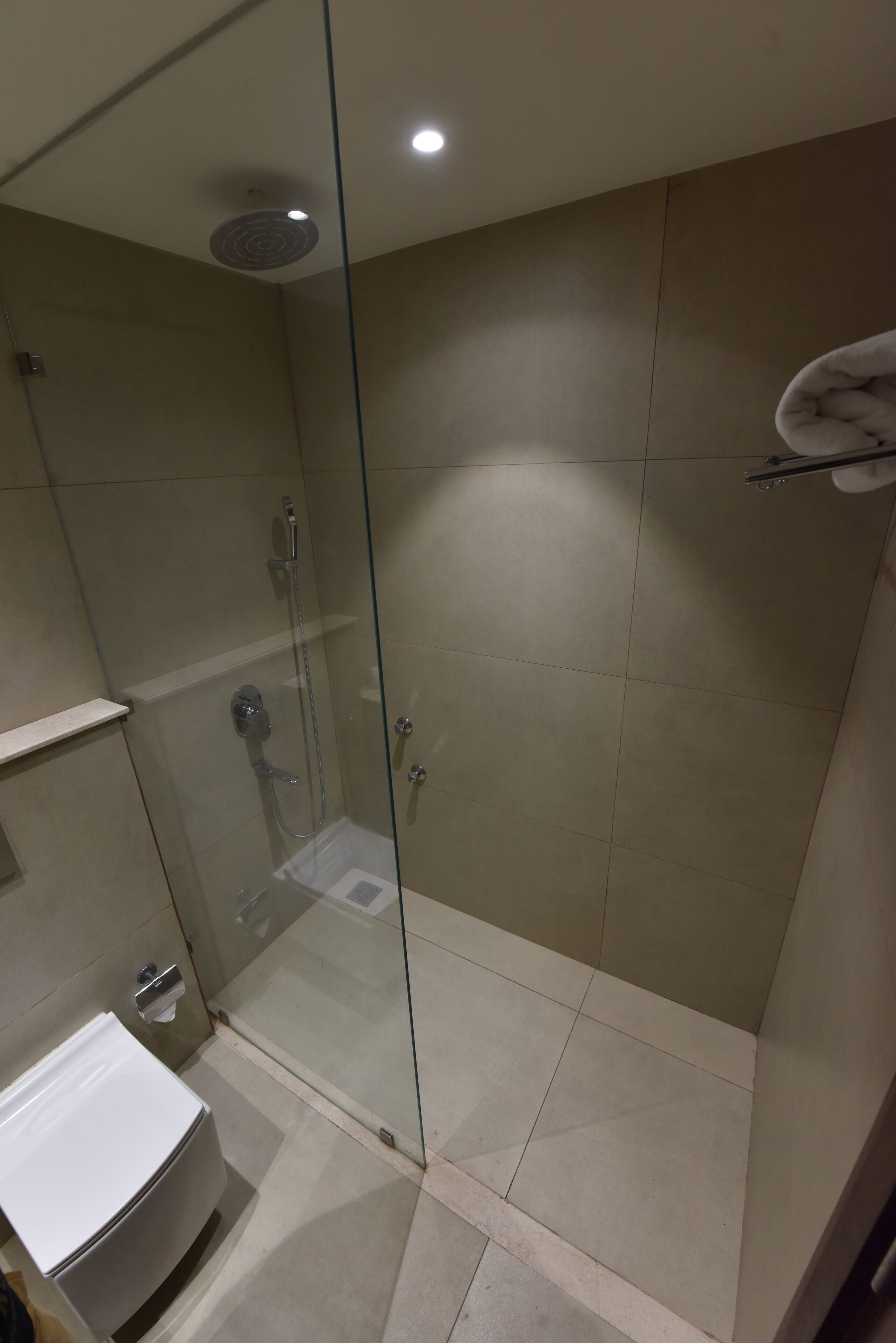 Un baño moderno con ducha de vidrio, lavamanos blanco y barra para toallas.