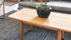 Ein modernes Wohnzimmer mit einem grauen Sofa, einem Holztisch, einer Stehlampe und einem Blumentopf.