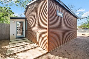 En liten, envåningsbyggnad med en fasad av korrugerad metall, en dörr med ett fönster och en liten veranda.