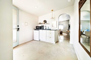 Una cocina moderna con armarios blancos, microondas integrado y cafetera.