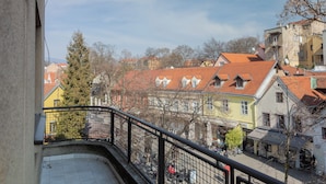 Ein Balkon mit Fliesenboden, Metallgeländer und Blick auf bunte Gebäude mit roten Dächern.