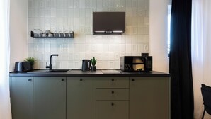 Eine moderne Küche mit schwarzem Arbeitsplatz, integriertem Mikrowellenherd, Kaffeemaschine und einer schwarzen Dunstabzugshaube.
