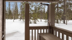 Een houten terras met uitzicht op een besneeuwd bos.