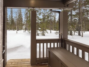 Une terrasse en bois offrant une vue sur une forêt enneigée.