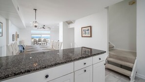 A modern kitchen with granite countertops, white cabinetry, and a view to the dining area. - Beautiful, modern, 4 bedroom oceanfront townhome! (Ocean City)