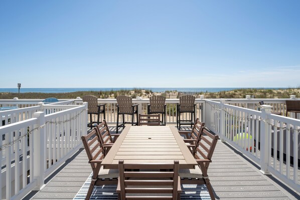 Une terrasse avec une table et des chaises en bois, donnant sur une plage.
