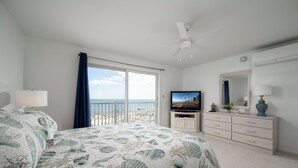 A bedroom with a bed, a television, a dresser, and a view of the beach. - Beautiful, modern, 4 bedroom oceanfront townhome! (Ocean City)