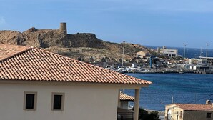 A coastal town with a prominent rocky hill and a tower. - Très bel Appartement de 71 m², vue sur mer 250 m de la Plage ,du Centre-ville (L'Île-Rousse)