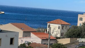 A coastal residential area with buildings featuring red-tiled roofs and a view of the sea. - Très bel Appartement de 71 m², vue sur mer 250 m de la Plage ,du Centre-ville (L'Île-Rousse)