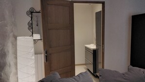 Ein Zimmer mit Holztür, einem weißen Heizkörper, einem Spiegel und einem weißen Waschbecken.