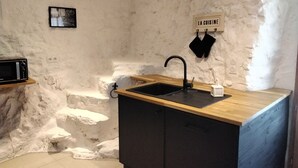 Eine Küche mit Holztischplatte, schwarzen Schränken, einem schwarzen Spülbecken und einer weißen Wand mit dem Schild 'LA CUISINE'.