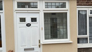 A white door with the number 18, a small window above it, and a satellite dish on the wall. - Baraka House Royal Victoria London by OYO (London)