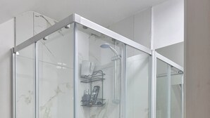 A modern bathroom with a glass-enclosed shower, a white sink, and a mirror. - Baraka House Royal Victoria London by OYO (London)