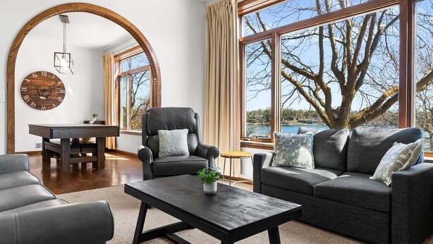 Een moderne woonkamer met een groot raam, een houten klok en een open haard.
