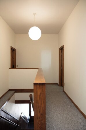 A room with a wooden staircase, a white ceiling light, and two wooden doors. - Loft above the Villager Pub with Round Lake marina sunsets — walk Bridge St + East Park. (Charlevoix)