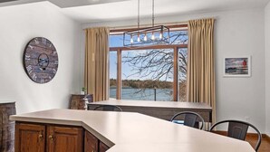 Een moderne keuken met een groot eiland, houten kastjes en uitzicht op een meer.