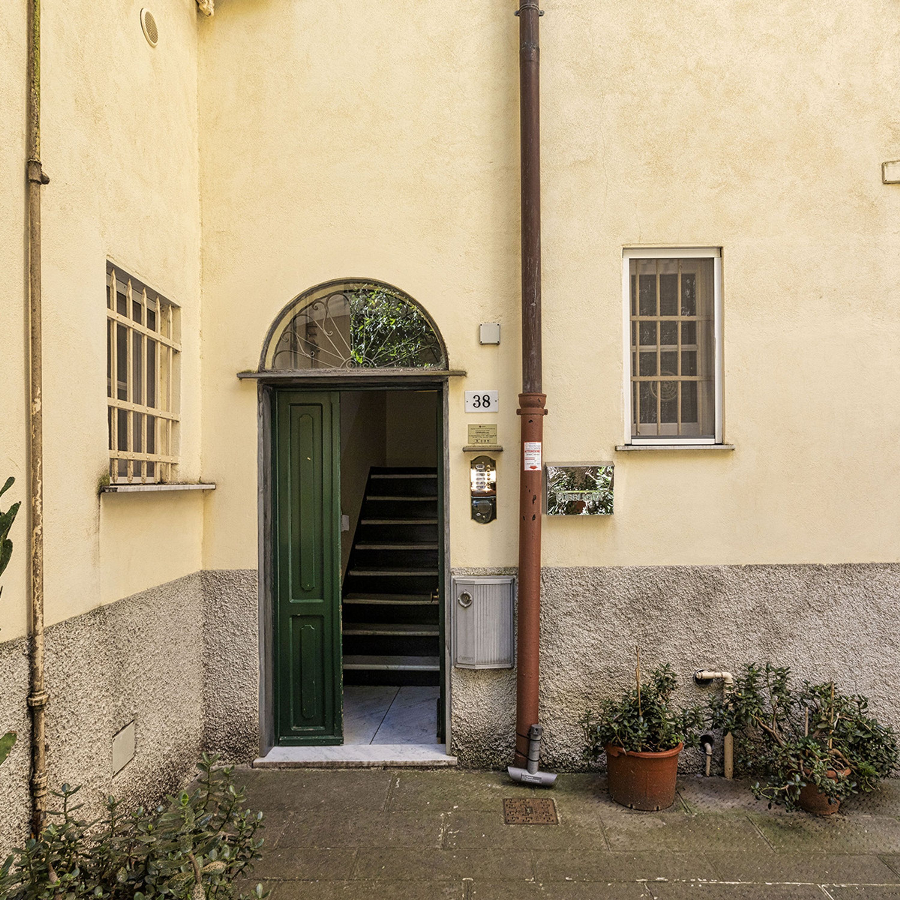 L'ingresso di un edificio con una porta verde, una scala che conduce all'interno, una cassetta postale e una piccola finestra.